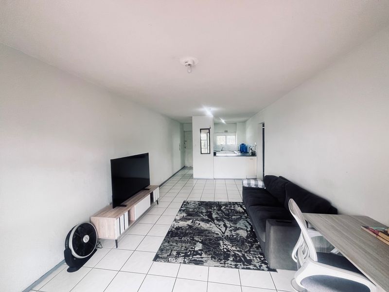 Open-plan living area featuring tiled flooring and a functional kitchen space with built-in cabinetry and countertops.