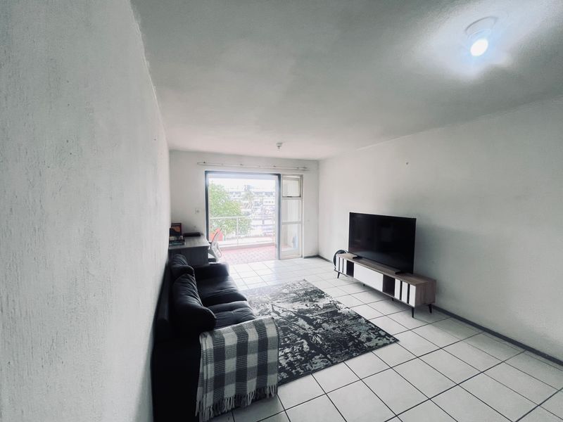 A living room featuring tiled flooring and a sliding glass door providing access to an outdoor balcony area.