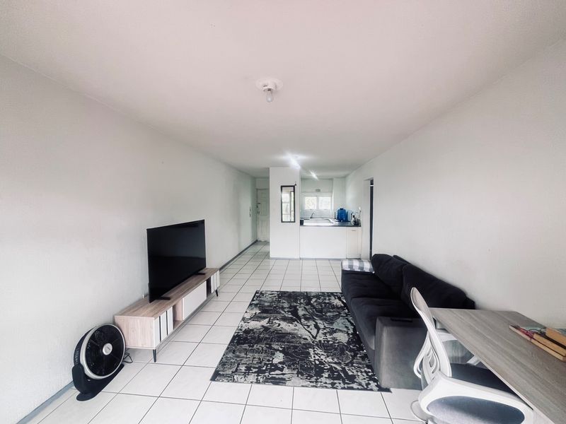 Open-plan living area featuring tiled flooring and a functional kitchen space with built-in cabinetry and countertops.
