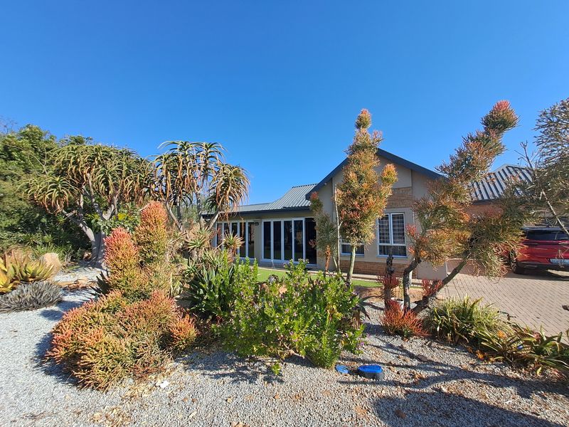 Front view of a well-maintained house featuring a paved driveway, modern sliding glass doors, and established low-maintenance garden landscaping.