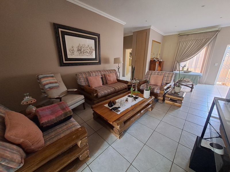 Spacious living room featuring neutral wall tones, tiled flooring, and natural light through a sliding door with access to the exterior.