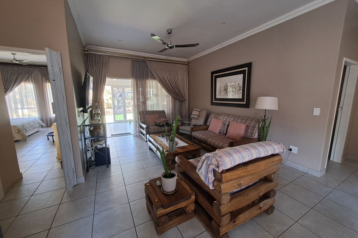 A spacious living room featuring tiled flooring, a ceiling fan, and large sliding glass doors that provide access to the outdoor patio area.