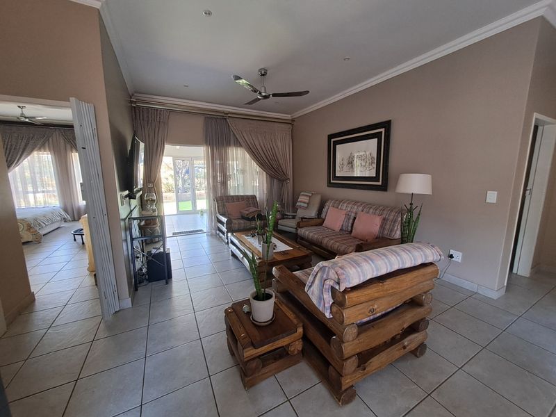 A spacious living room featuring tiled flooring, a ceiling fan, and large sliding glass doors that provide access to the outdoor patio area.