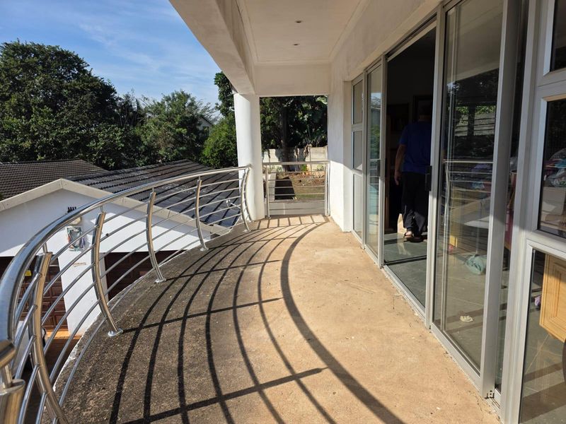 A curved balcony featuring a stainless steel balustrade and large sliding glass doors, offering an elevated outdoor space with potential for cosmetic enhancement.