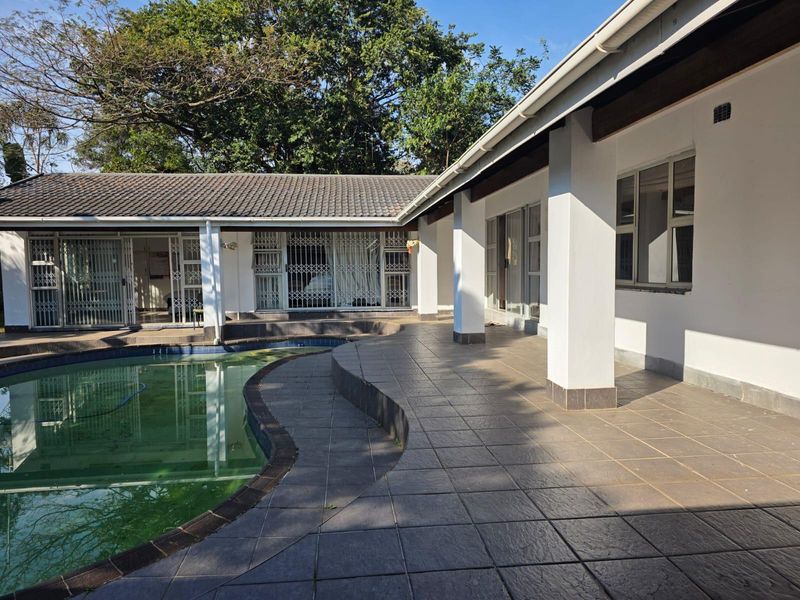 Spacious outdoor patio area featuring tiled flooring, direct access to the swimming pool, and secure sliding door entrances to the main house.
