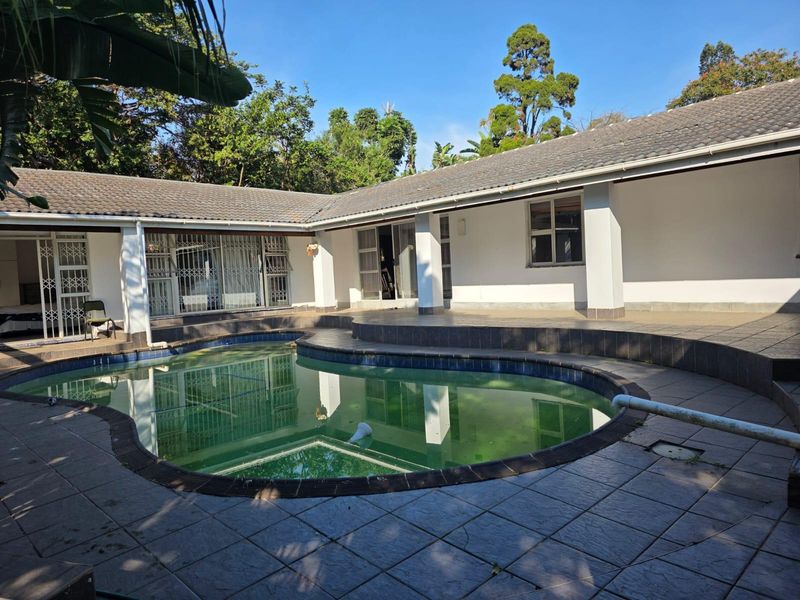 Outdoor pool area featuring a tiled deck, covered patio space, and direct access to the home via sliding doors with security gates.