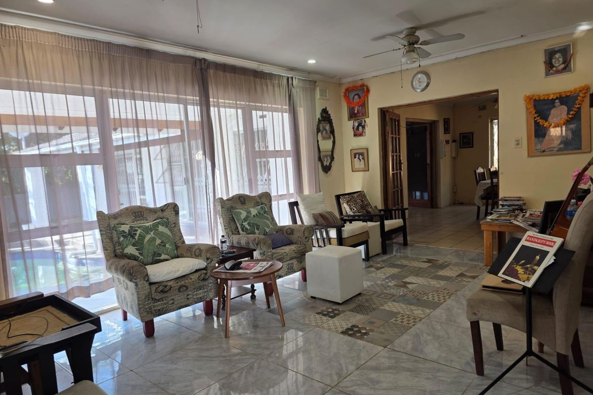Spacious living room featuring large sliding glass doors, tiled flooring, and ceiling fans, offering a bright and functional layout.