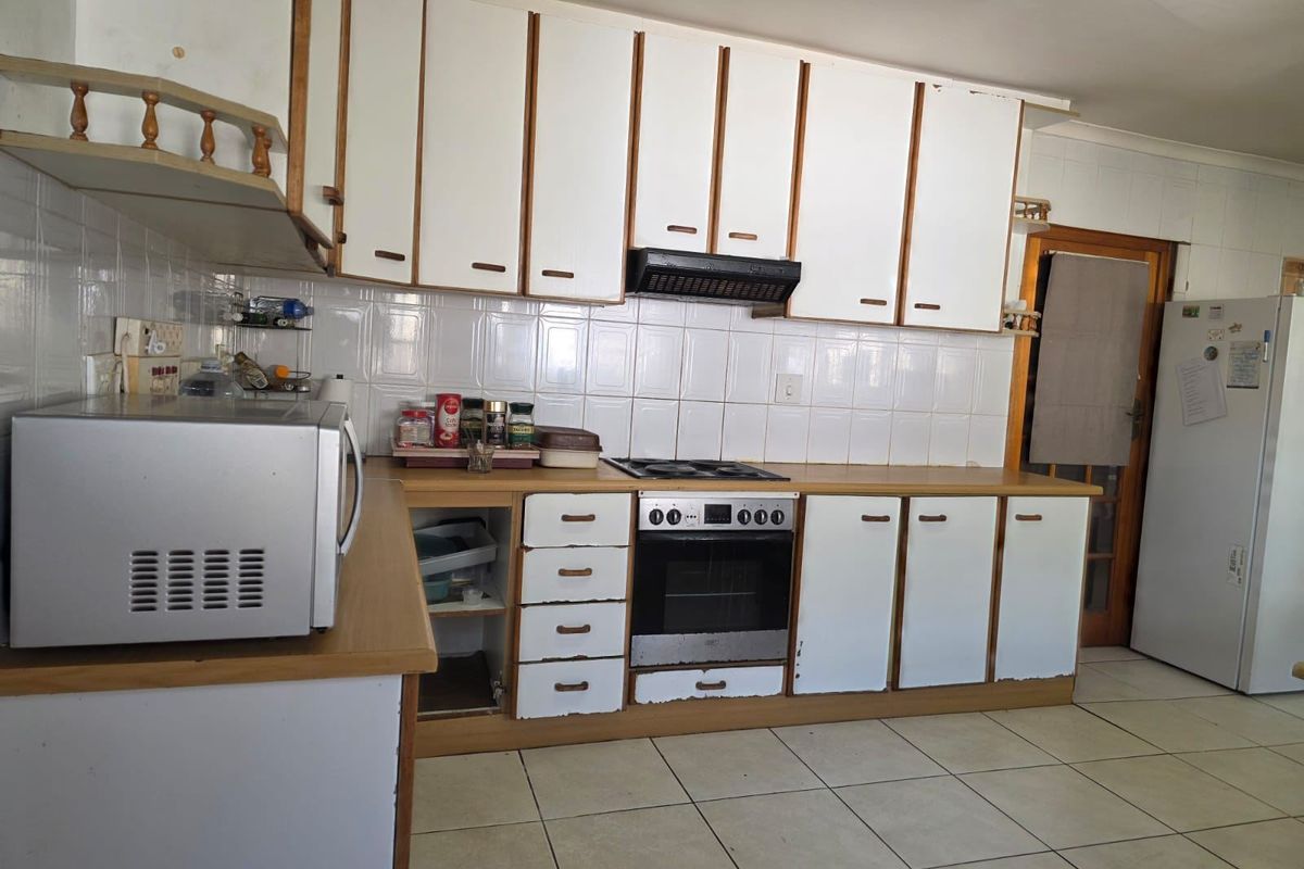 A functional kitchen featuring white cabinetry, tiled backsplash, and built-in cooking appliances, currently showing signs of wear and requiring cosmetic updates.