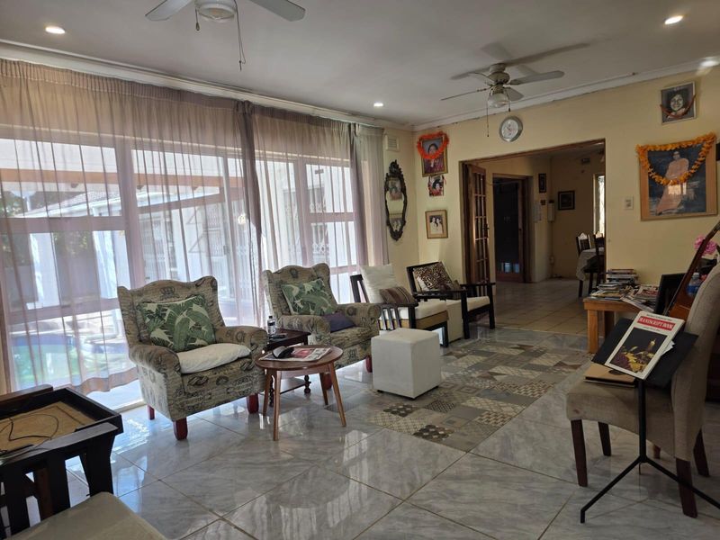 Spacious living room featuring large sliding glass doors, tiled flooring, and ceiling fans, offering a bright and functional layout.