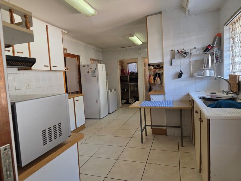 A functional kitchen featuring tiled flooring, ample built-in cabinetry, laminate countertops, and a double sink, offering potential for modern updates.