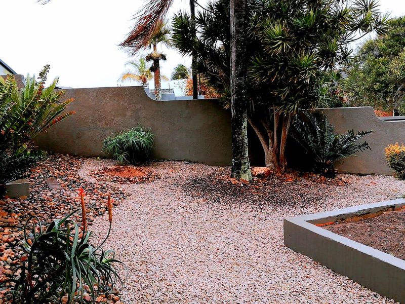 A low-maintenance garden area featuring gravel landscaping, a raised garden bed, and a solid boundary wall.