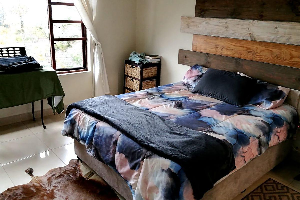 A bedroom featuring tiled flooring and a custom timber feature headboard, offering a functional space with natural light.