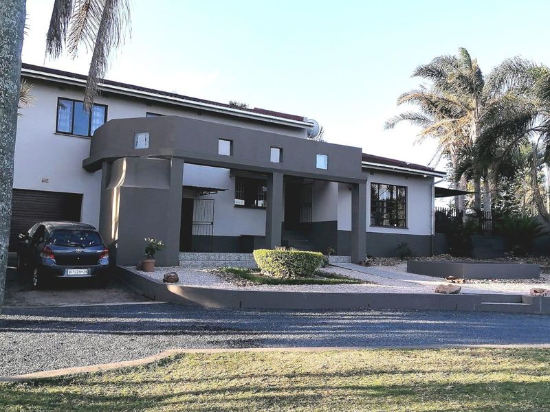 Front elevation of a residential house featuring a covered entrance porch, gravel landscaping, and a paved driveway with garage access.