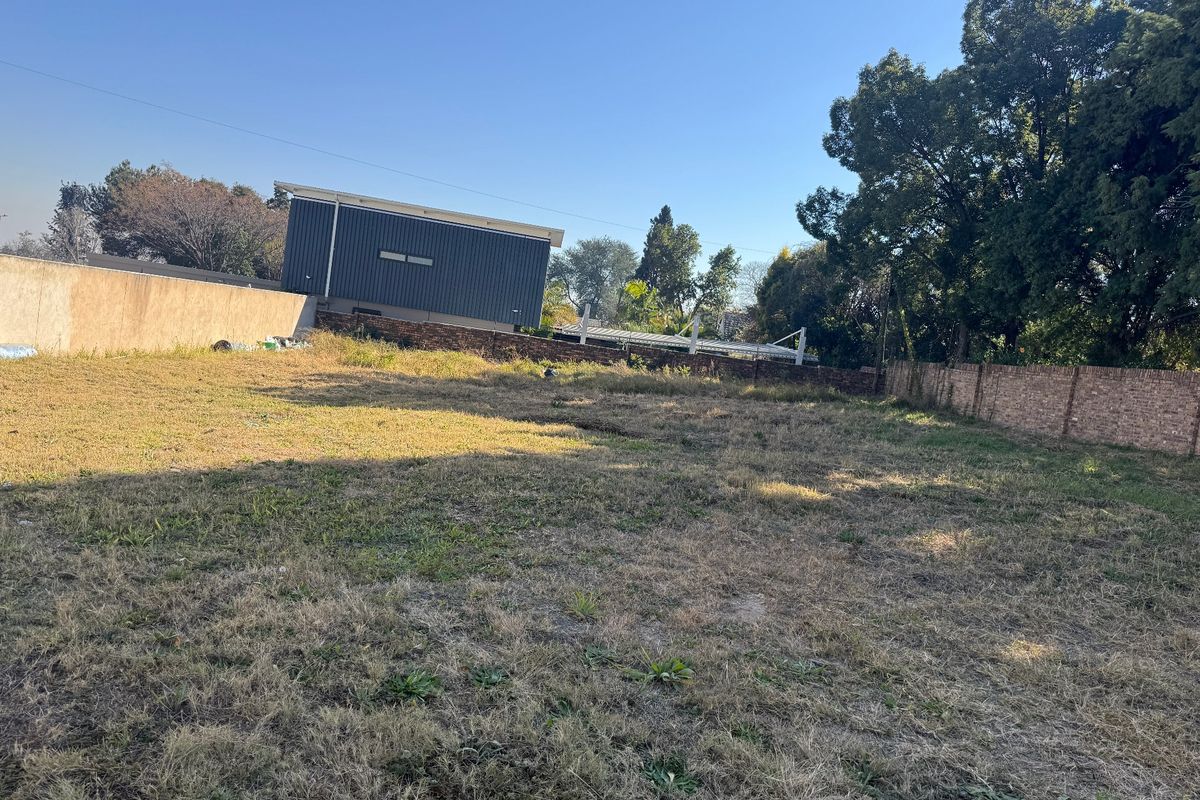 A vacant residential plot featuring established perimeter brick and concrete boundary walls, ready for development.