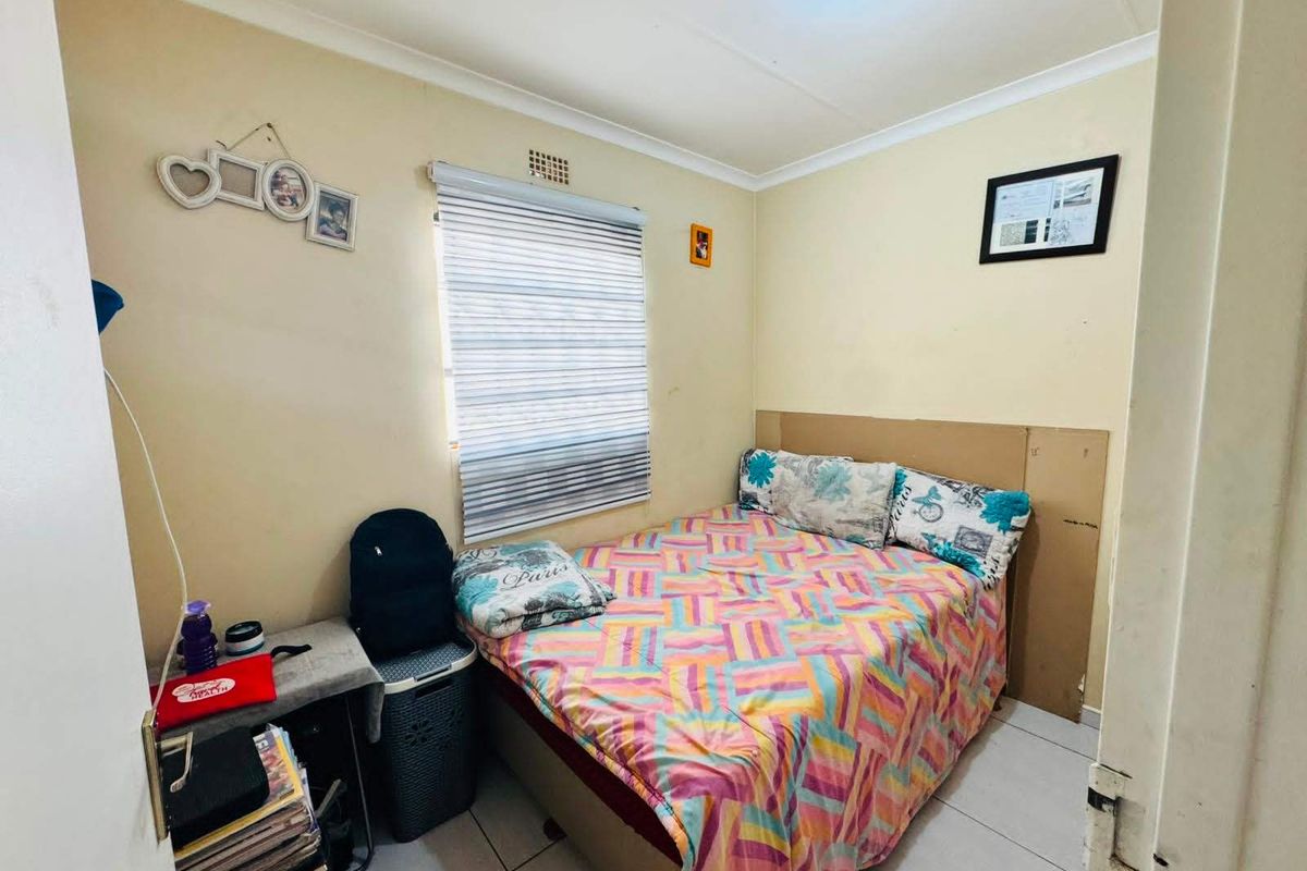 A compact bedroom featuring tiled flooring and a window with a roller blind, requiring minor cosmetic updates to improve the overall finish.