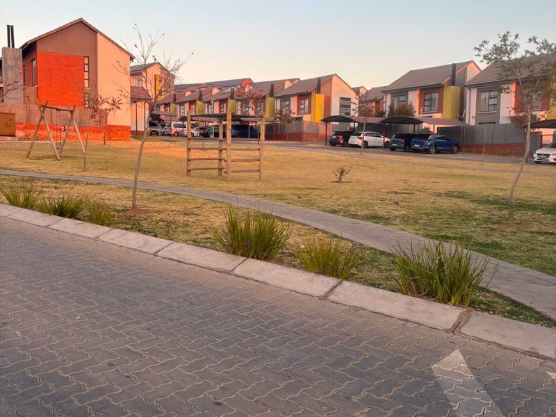 A view of the communal grounds and residential apartment blocks featuring paved driveways, carports, and landscaped lawn areas.