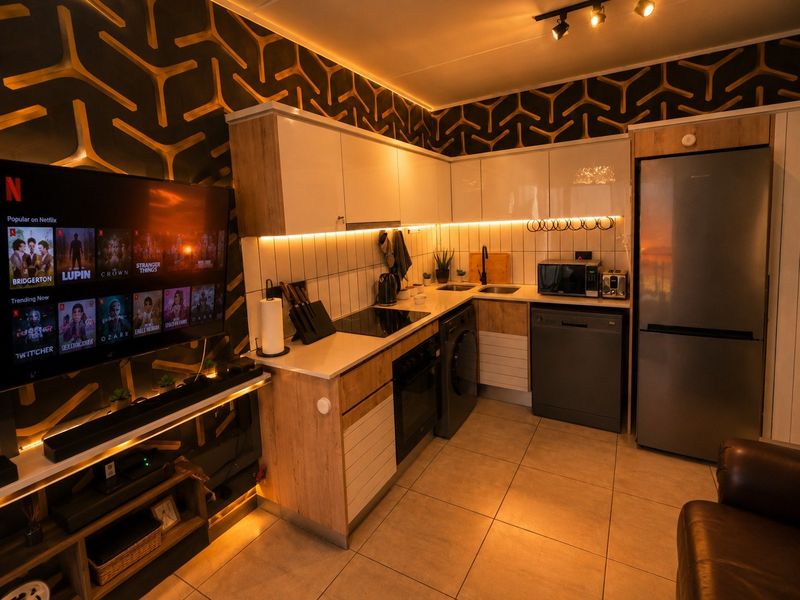 Modern open-plan kitchen featuring sleek cabinetry, integrated appliances, and warm under-cabinet lighting, seamlessly connected to the living area.