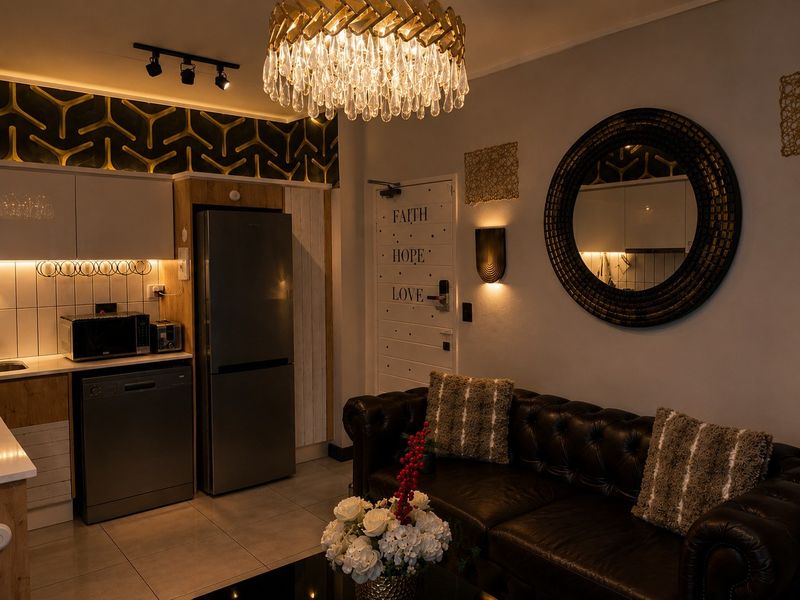 A well-appointed open-plan living and kitchen area featuring modern cabinetry, tiled flooring, and elegant lighting fixtures in a compact apartment setting.