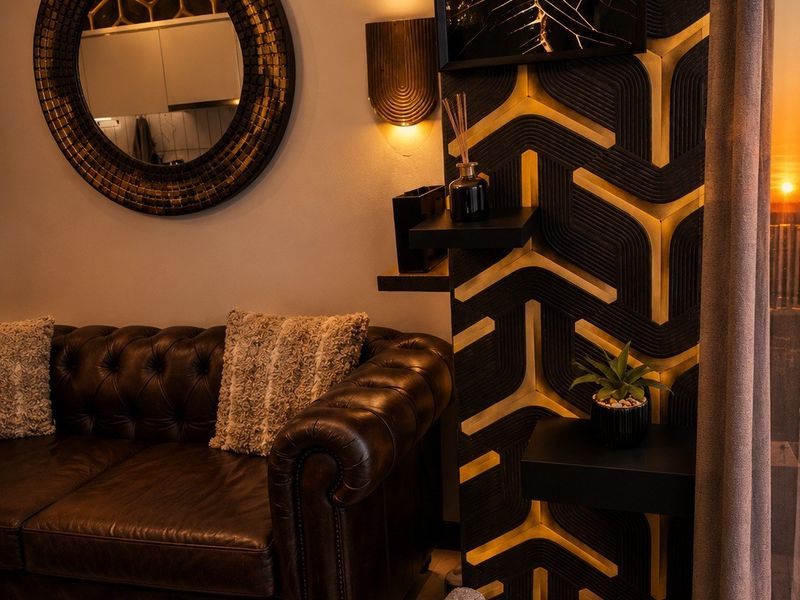 A stylishly appointed living area featuring custom geometric wall paneling, integrated accent lighting, and high-quality finishes.