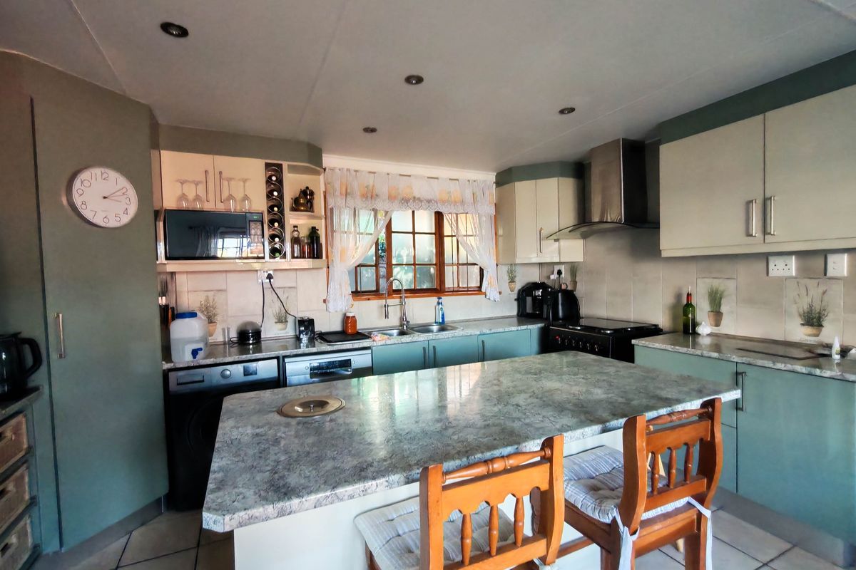 A functional kitchen featuring a central island, built-in cabinetry, stainless steel extractor fan, and tiled backsplash with ample counter space.