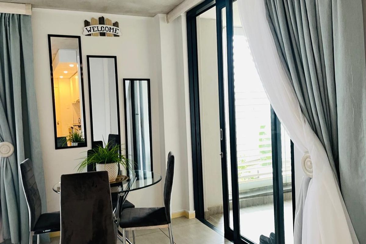 A bright living area featuring large sliding glass doors that provide access to an outdoor space, complemented by tiled flooring and an exposed concrete ceiling.