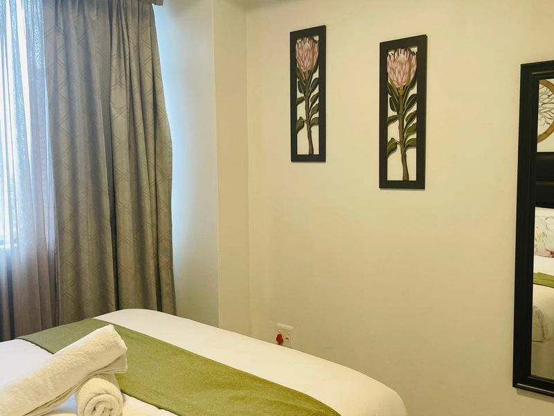 A well-maintained bedroom featuring neutral walls, floor-to-ceiling curtains, and a functional layout.