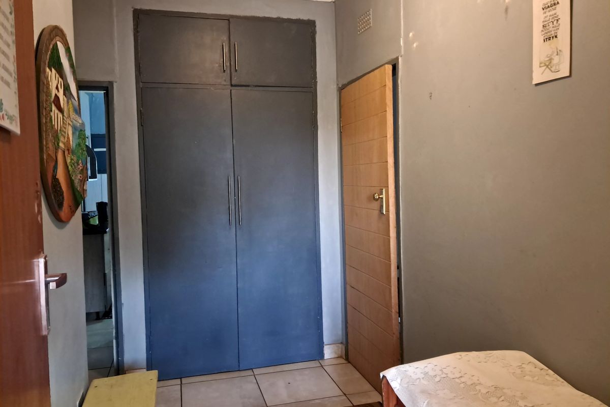 A bedroom featuring built-in cupboards, tiled flooring, and access to adjacent rooms through internal doors.
