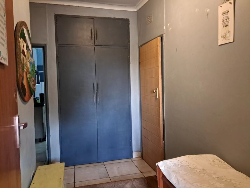 A bedroom featuring built-in cupboards, tiled flooring, and access to adjacent rooms through internal doors.