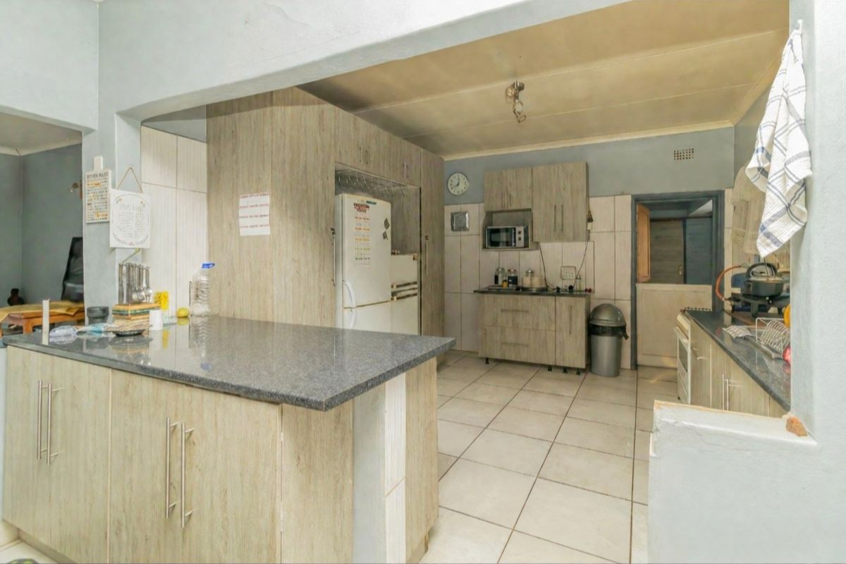 A functional kitchen featuring laminate cabinetry, stone countertops, and tiled flooring, offering a practical layout with integrated storage and workspace.