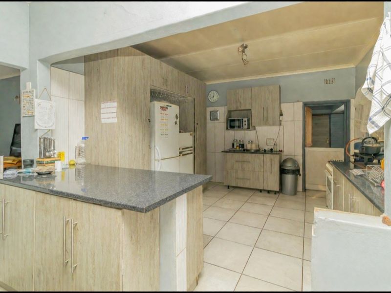 A functional kitchen featuring laminate cabinetry, stone countertops, and tiled flooring, offering a practical layout with integrated storage and workspace.