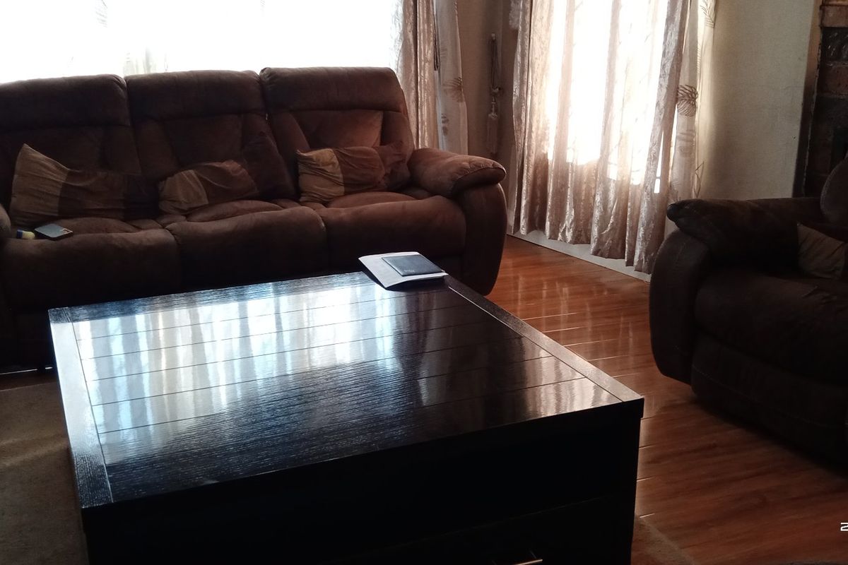 A living room featuring laminate flooring and a brick fireplace, offering a cozy and traditional atmosphere.
