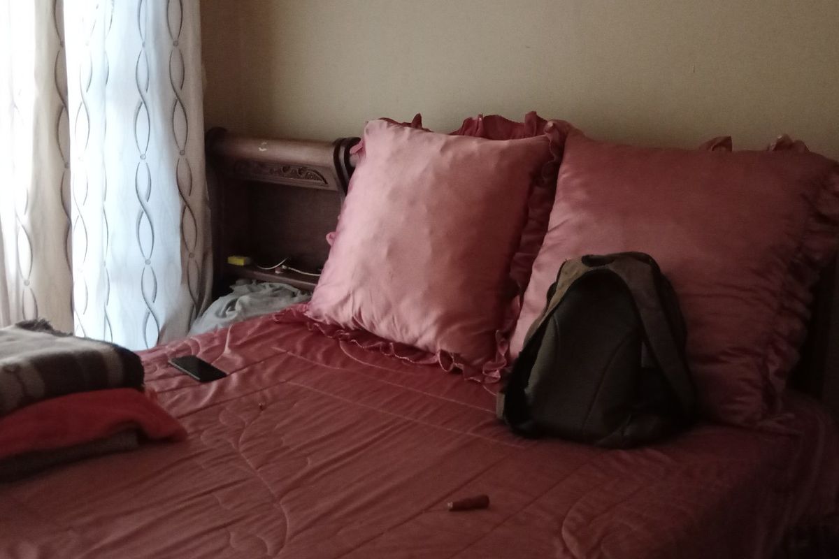 A bedroom interior featuring a bed positioned against a wall with window curtains.