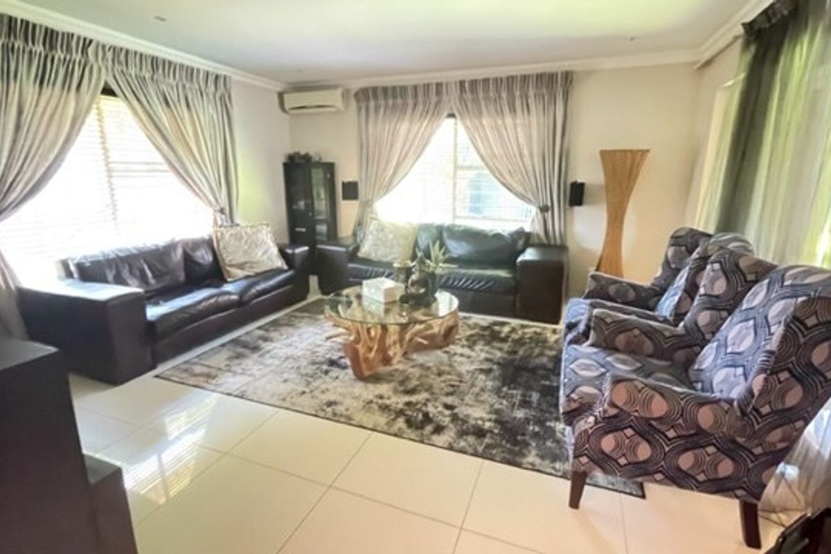 A spacious living room featuring tiled flooring, recessed downlighting, and a wall-mounted split-system air conditioning unit.