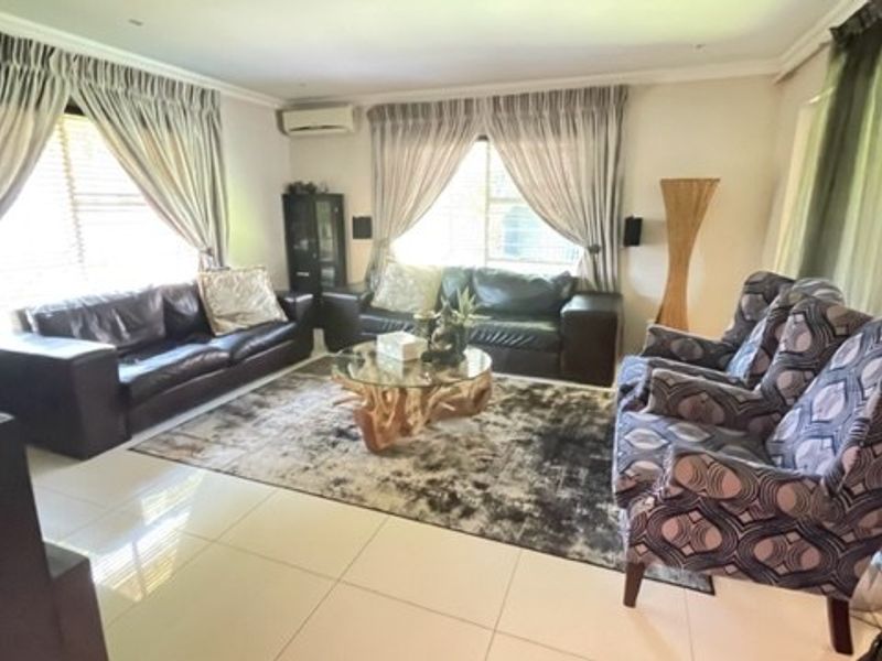 A spacious living room featuring tiled flooring, recessed downlighting, and a wall-mounted split-system air conditioning unit.