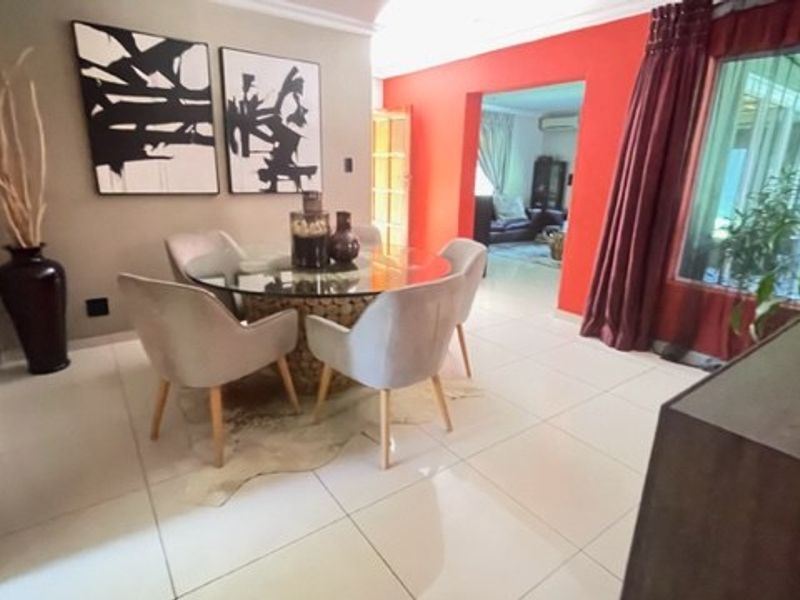 A dining area featuring large format floor tiles, coved ceilings, and a sliding glass door providing access to the exterior.