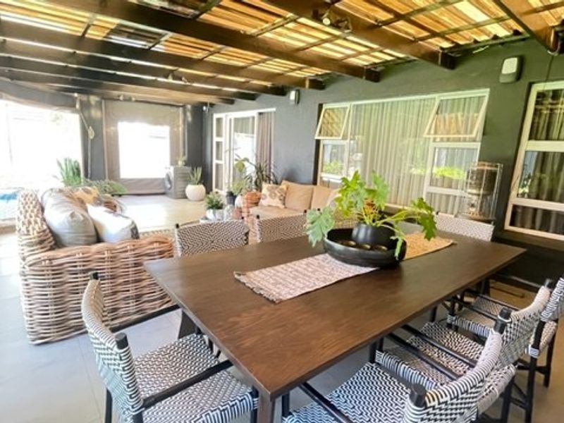 Spacious covered patio featuring a timber pergola roof, tiled flooring, and large sliding glass doors providing seamless indoor-outdoor flow.