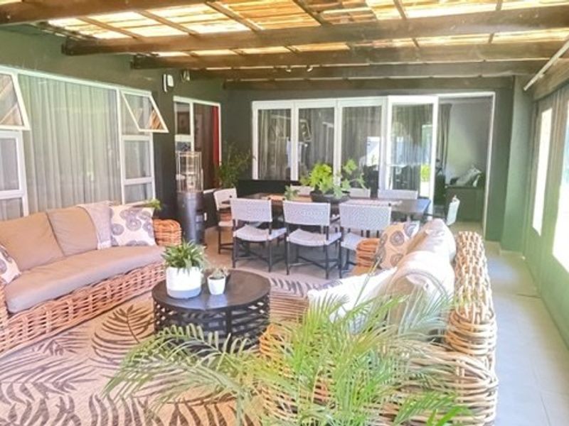 A spacious covered patio featuring a timber pergola roof, tiled flooring, and large sliding glass doors providing seamless access to the interior living areas.