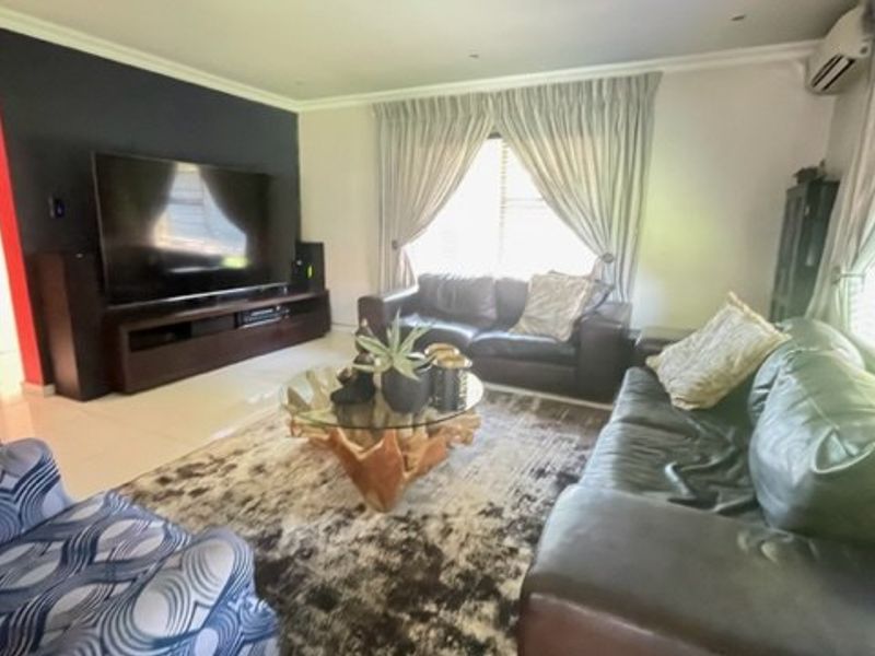 A comfortable living room featuring tiled flooring, recessed lighting, and a wall-mounted air conditioning unit, providing a functional and well-maintained space.