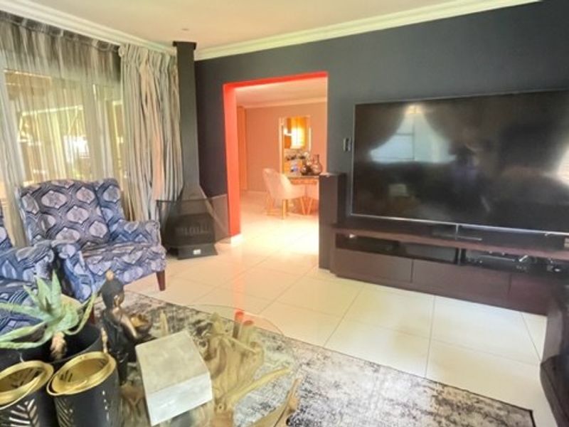 Spacious living room featuring large format floor tiles, a modern freestanding fireplace, and direct access to the outdoor area through sliding glass doors.