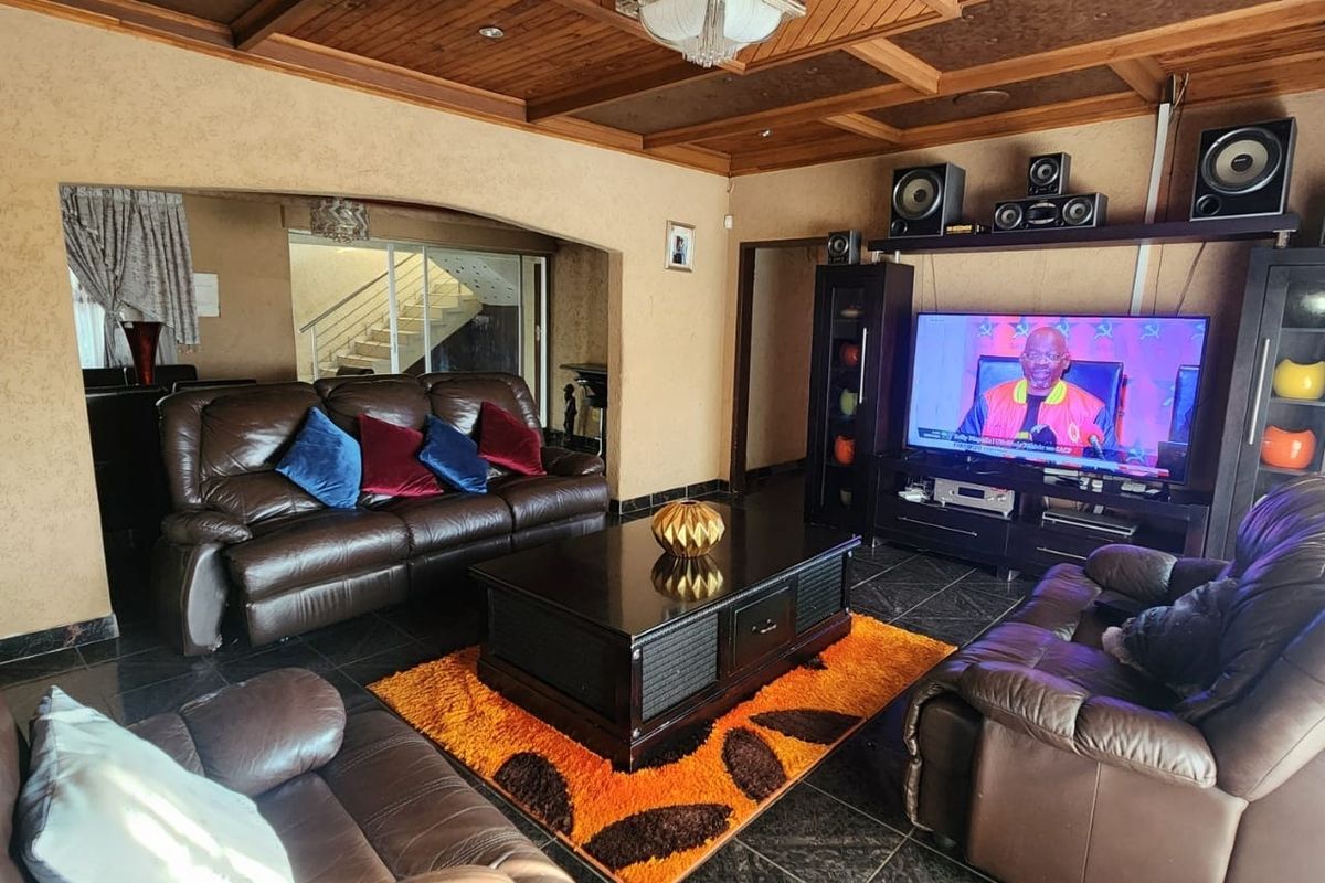 Spacious living room featuring a distinctive coffered timber ceiling, tiled flooring, and integrated media cabinetry.