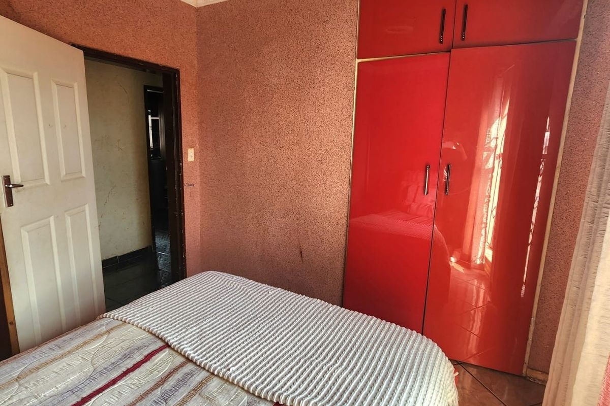 Bedroom featuring a built-in red wardrobe, tiled flooring, and decorative crown molding. The room requires cosmetic updates to modernize the wall and ceiling finishes.