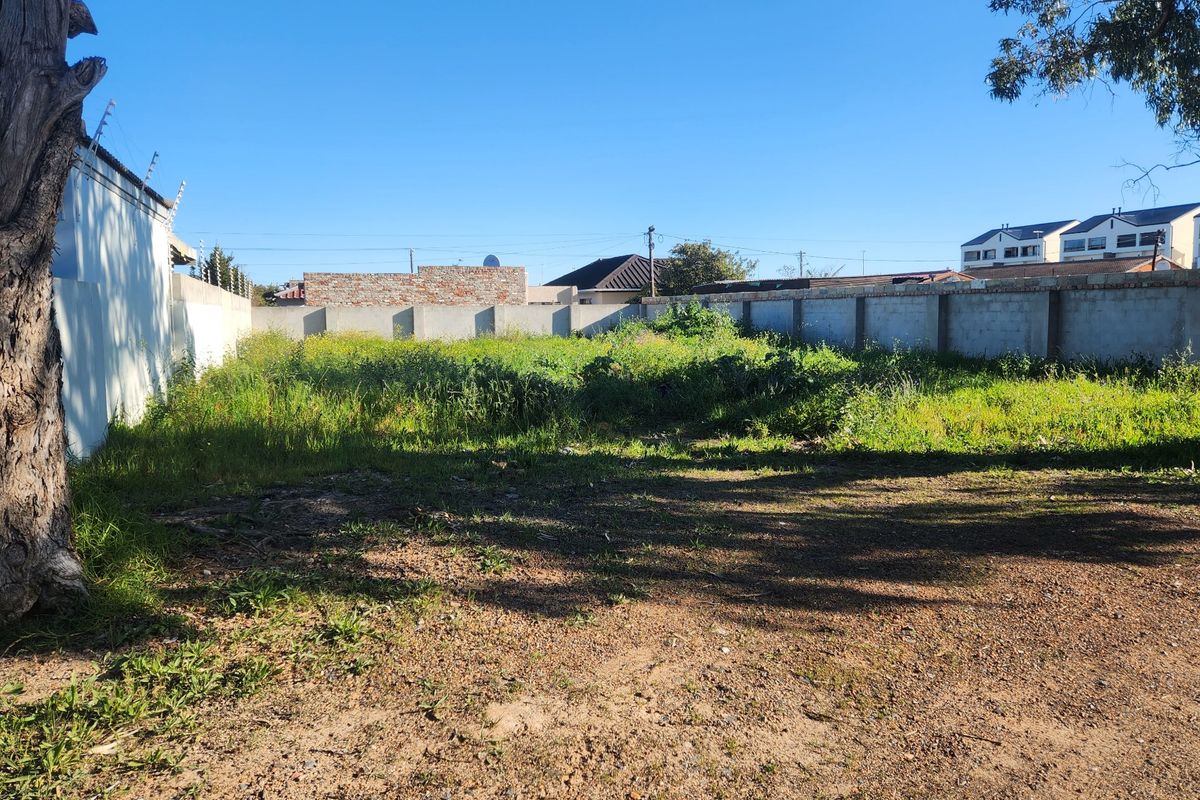 A vacant residential plot featuring perimeter walling with electric fencing, offering a clear space for future development.