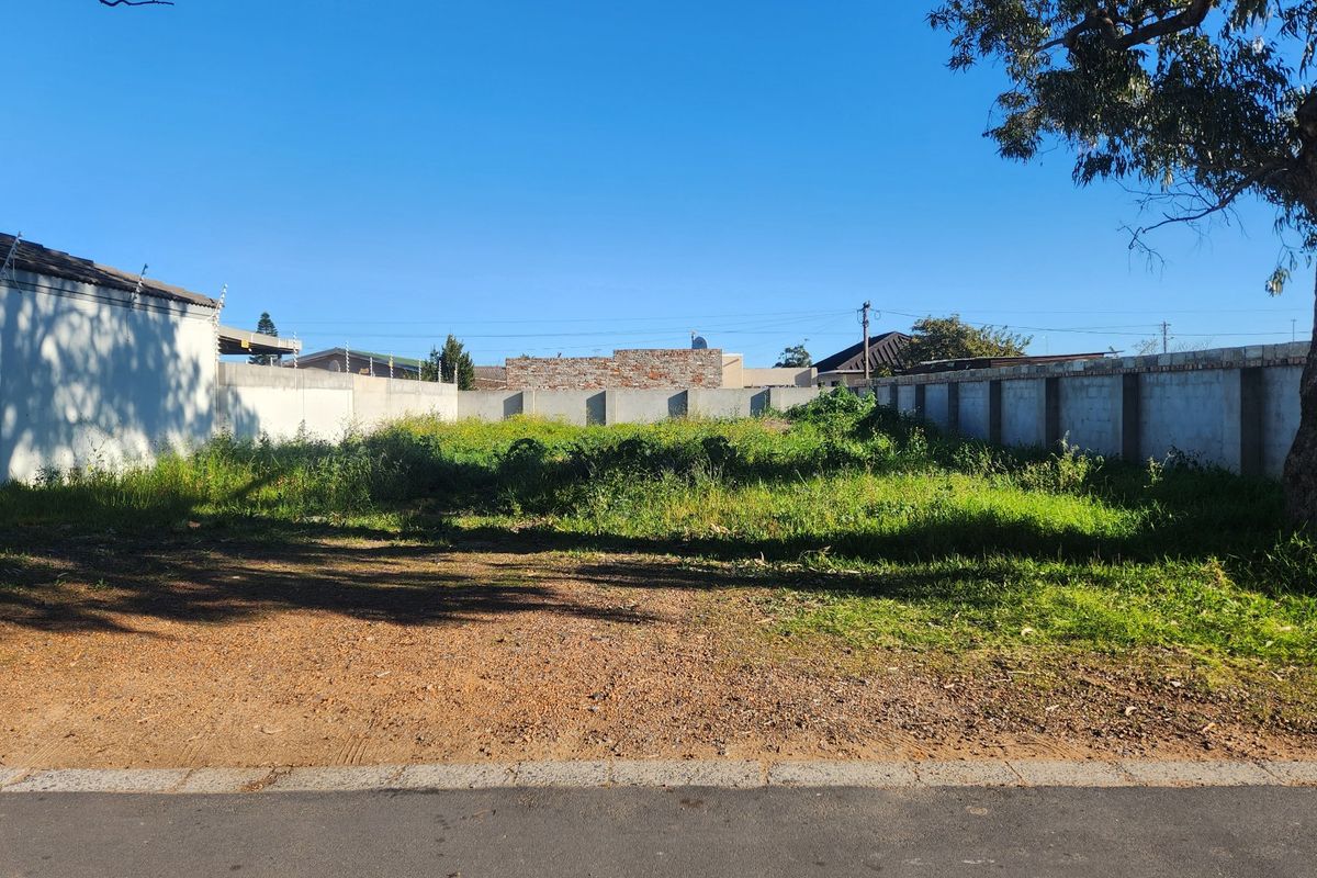 A vacant residential plot featuring perimeter boundary walls and direct road access, ready for development.