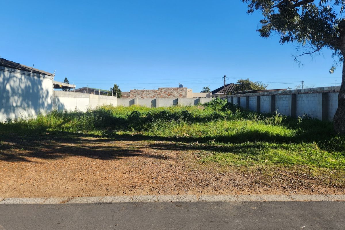 A vacant residential plot featuring a perimeter wall with electric fencing and an established tree, ready for development.