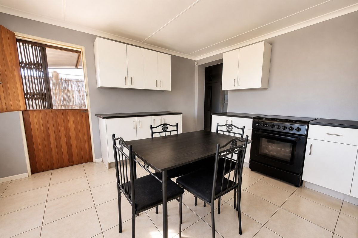 A functional kitchen featuring white cabinetry, dark countertops, a freestanding stove, and tiled flooring, with direct access to an outdoor area via a stable door.