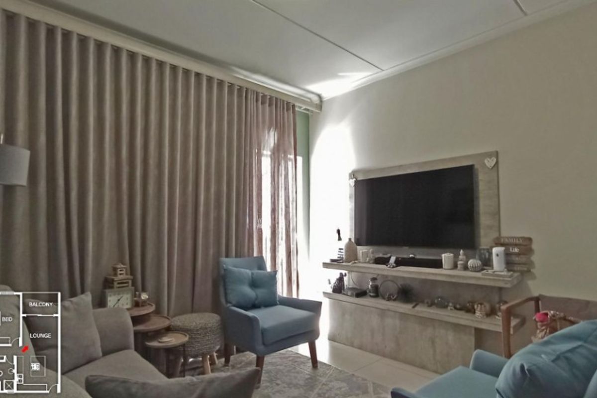 A comfortable living room featuring a built-in media console, tiled flooring, and floor-to-ceiling curtains providing access to the balcony.