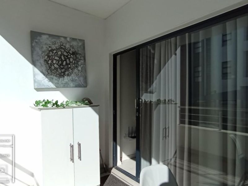 A covered balcony area featuring a large sliding glass door providing access to the interior living space.