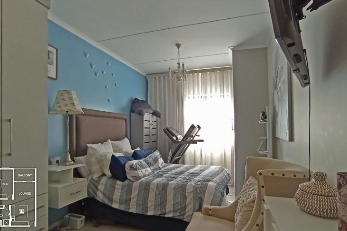 A bedroom featuring a built-in wardrobe and large window with curtain tracks, providing natural light and functional storage space.