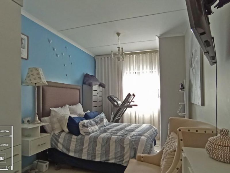 A bedroom featuring a built-in wardrobe and large window with curtain tracks, providing natural light and functional storage space.