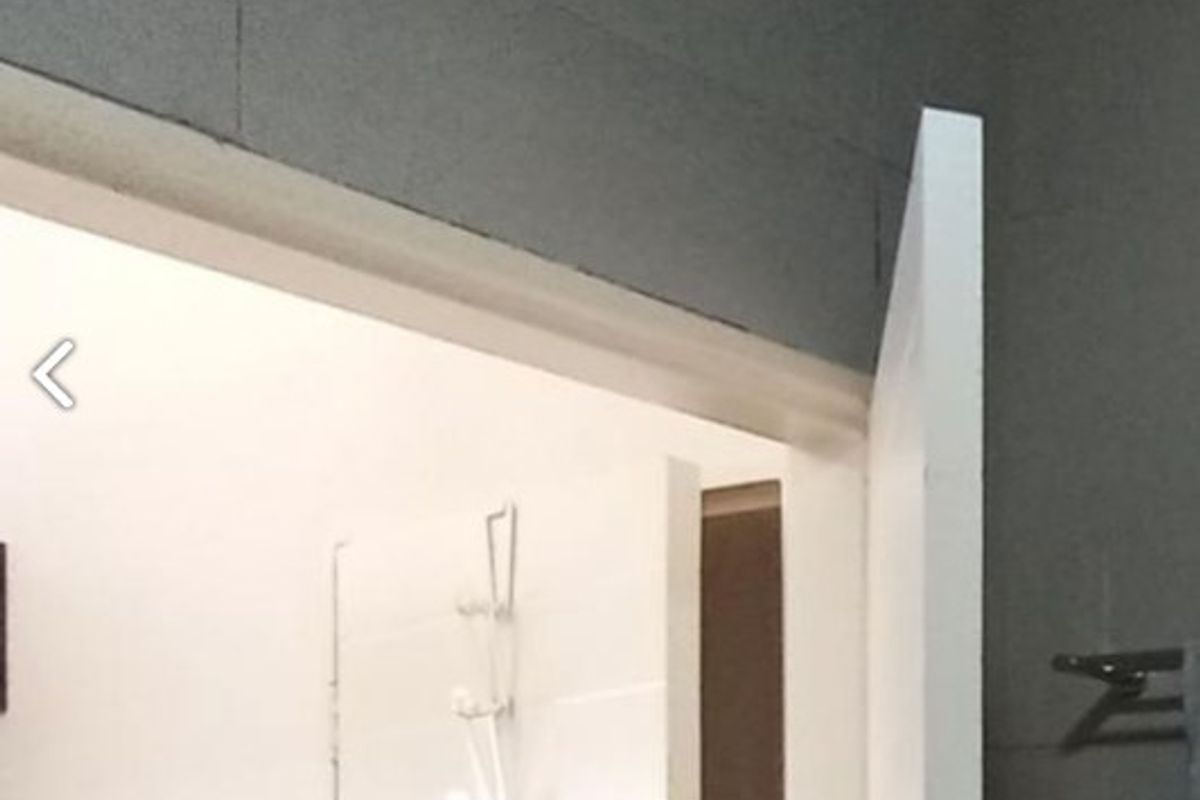 A view into a bathroom featuring tiled walls, a shower fixture, and a wall-mounted towel rail.